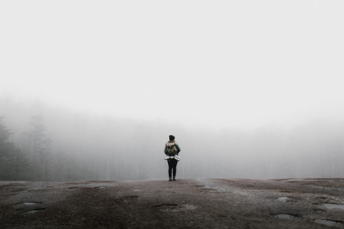 Person with backpack in foggy forest
