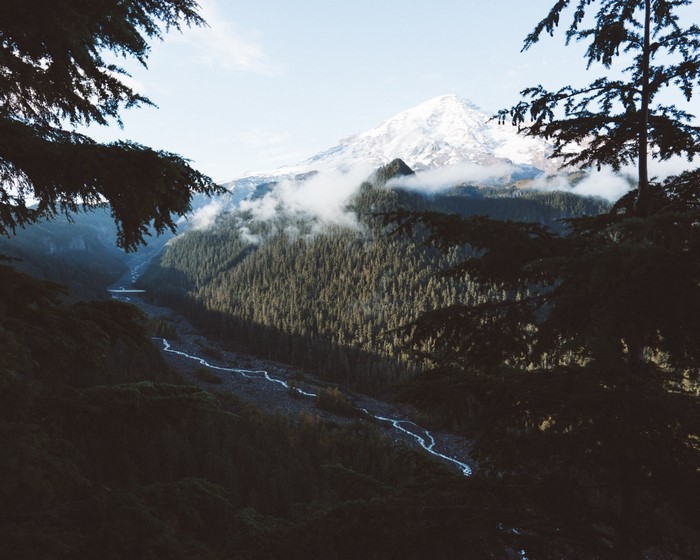 Snow-capped mountain peak above a forested valley with a river