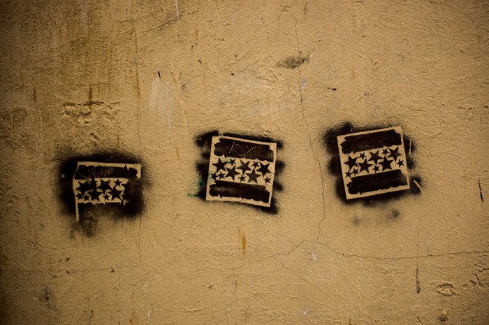 Three stencil graffiti flags with stars on a textured wall