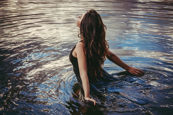 Woman in black dress wading in water