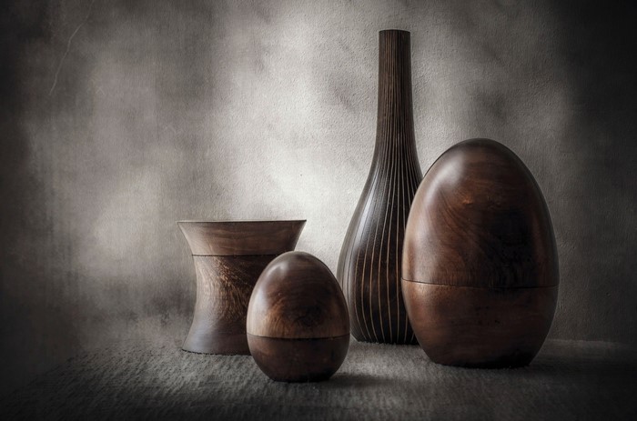 Wooden vases and egg-shaped sculptures on a textured background