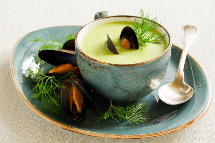 Mussel soup with dill and spoon on a plate
