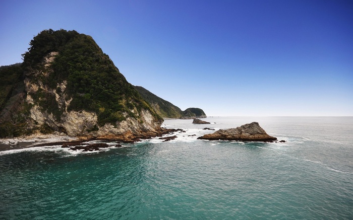 Rocky coastline with green hills and blue sky