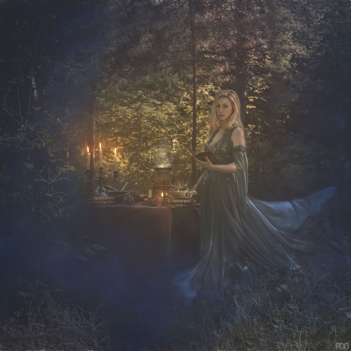 Woman in a dress reading a book in a forest