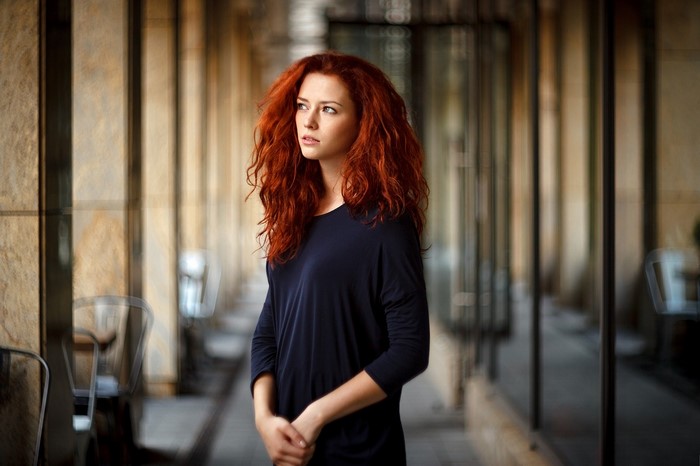Woman with long red wavy hair wearing a dark blue dress