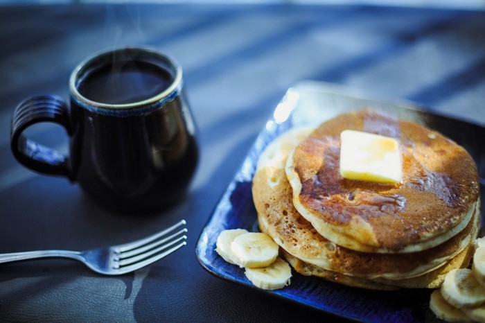 Pancakes with butter and syrup, coffee, and fork