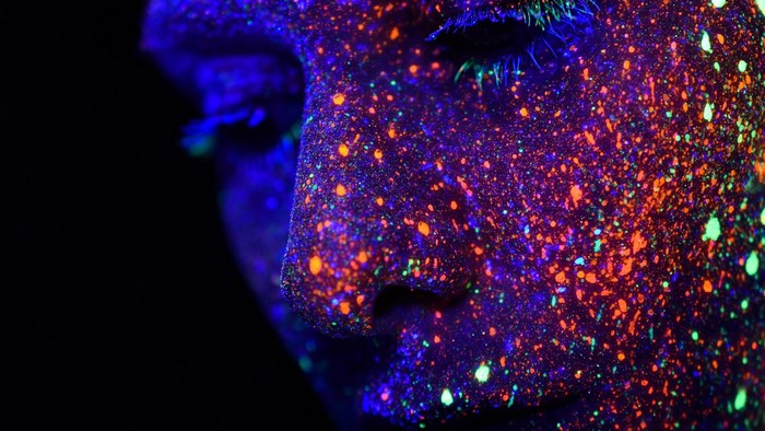 Face covered in neon paint splatters