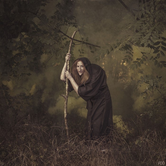 Witch with a staff in a dark forest
