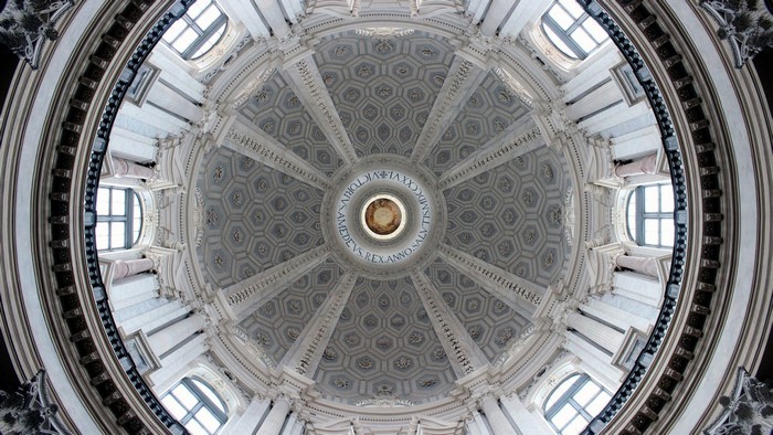 Interior of a grand dome with ornate carvings and windows
