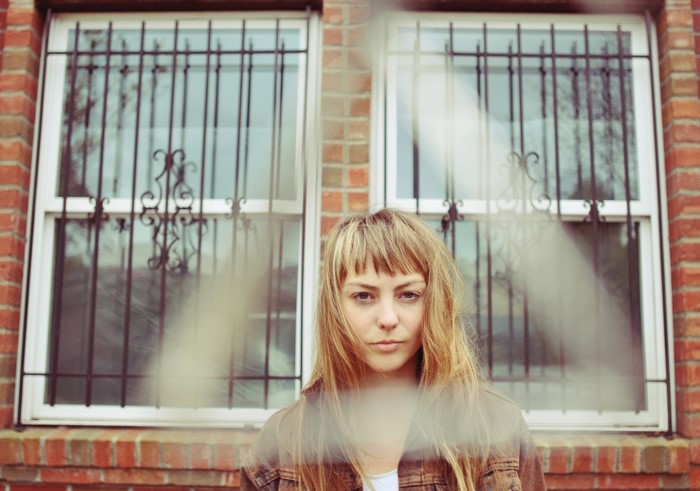 Angel Olsen in front of a brick building with windows