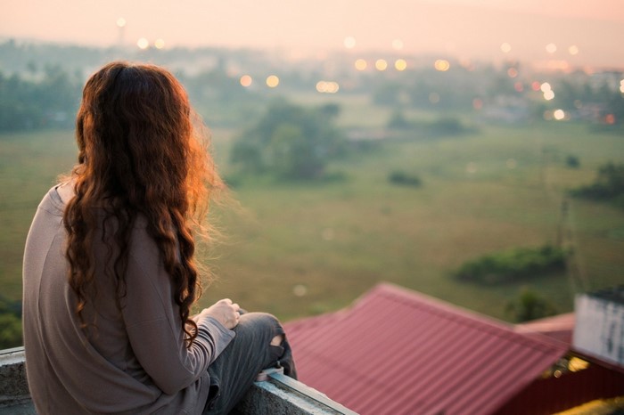 Woman with wavy hair sitting on a rooftop at sunset