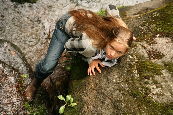 Girl in plaid shirt and jeans in a stream
