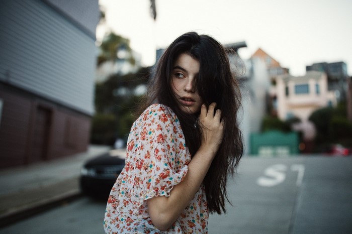 Woman in floral dress looking over shoulder on street
