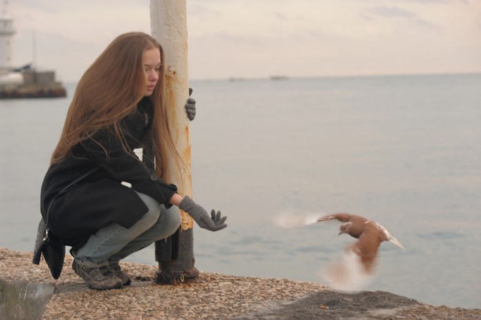Girl feeding a bird by the sea