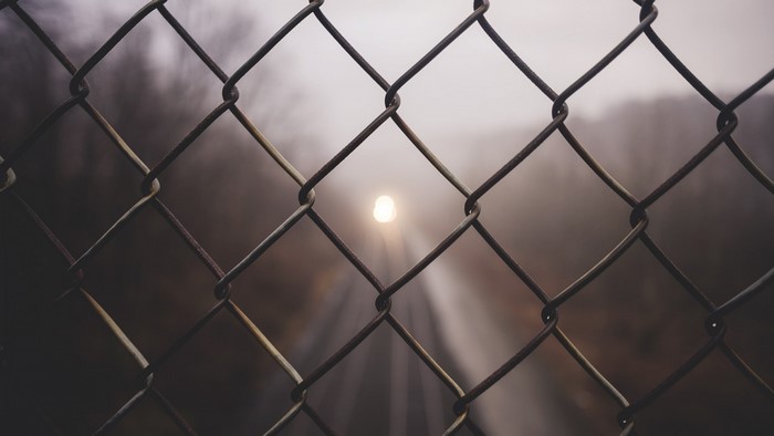 Chain link fence with light in fog