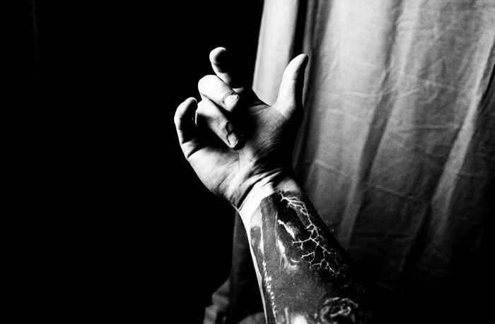 Man's tattooed arm and hand in darkness