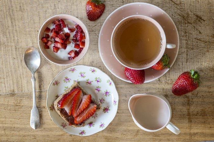 Breakfast with strawberries, yogurt, toast, and tea