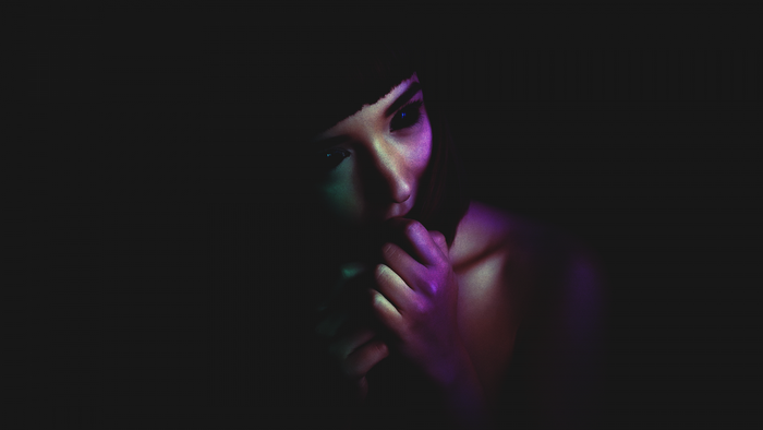 Woman with hands covering mouth in purple and green light