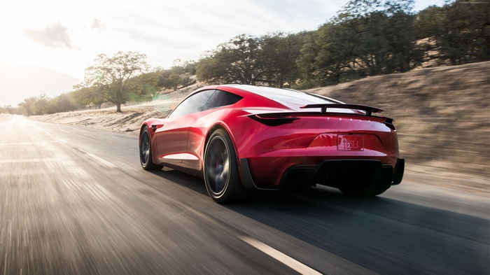 Red Tesla Roadster driving on a road