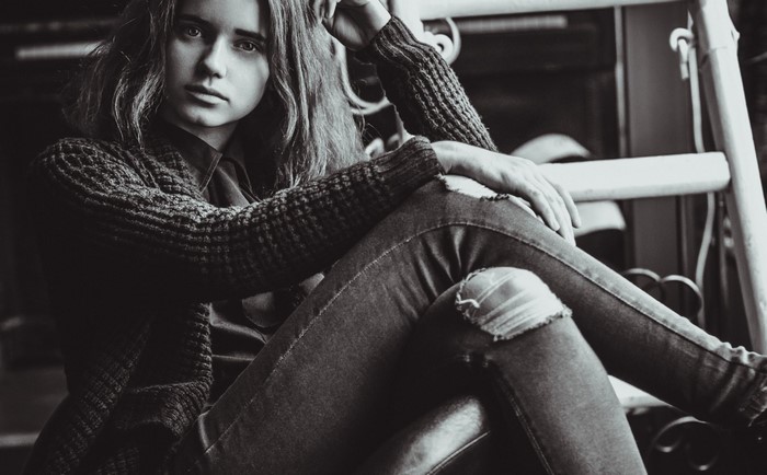 Monochrome portrait of a young woman in torn jeans