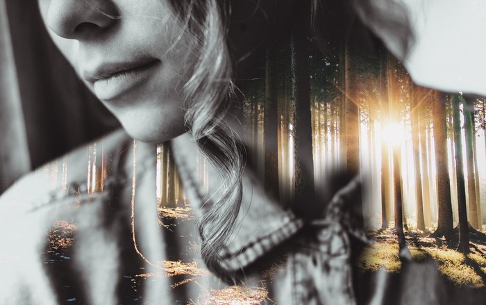 Double exposure of a woman and a forest with sunlight