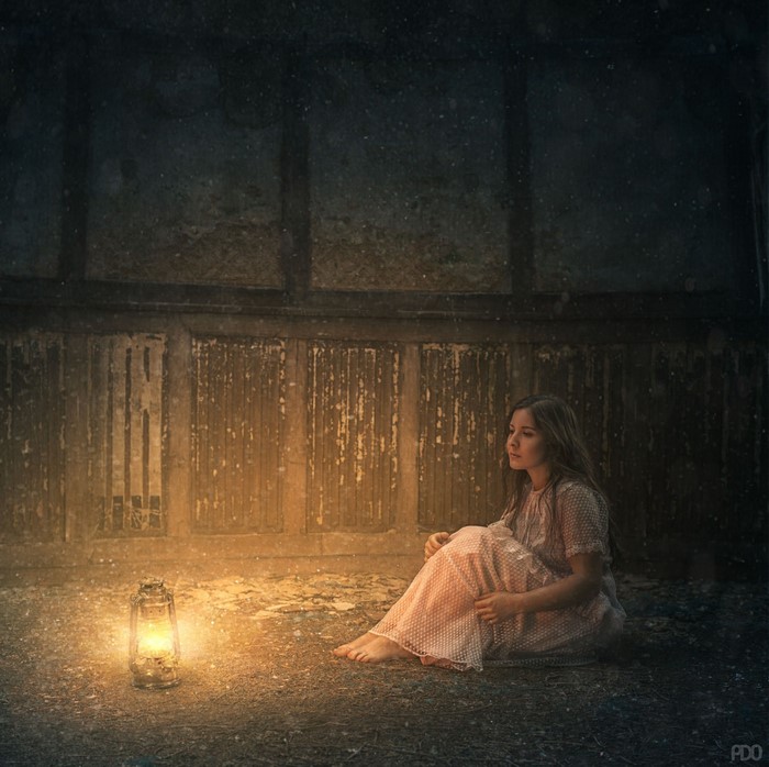 Woman sitting by a lantern in darkness