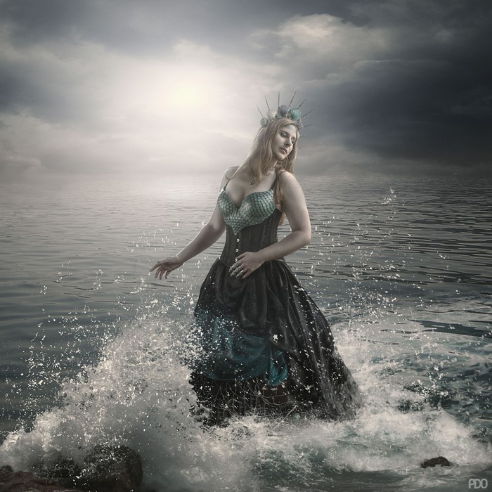 Woman in a fantasy dress standing in the ocean waves