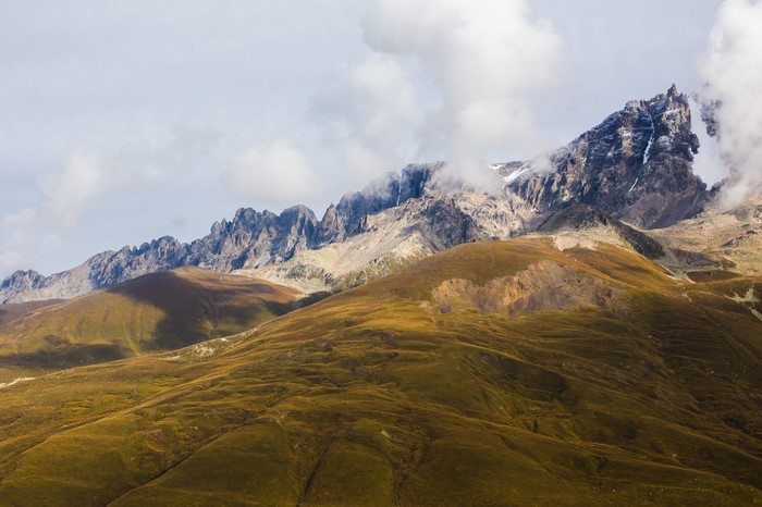 Mountain range with grassy hills and clouds