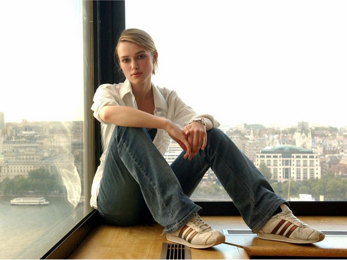 Keira Knightley sitting by a window overlooking a city