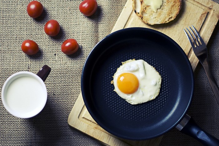 Fried egg in a pan with tomatoes and toast