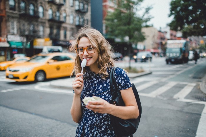 Woman eating with a spoon on a city street