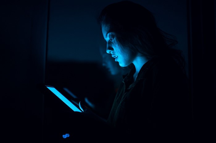 Woman illuminated by blue light from a phone