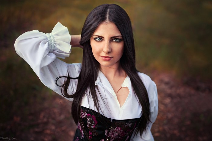 Woman with long black hair in a white shirt and corset