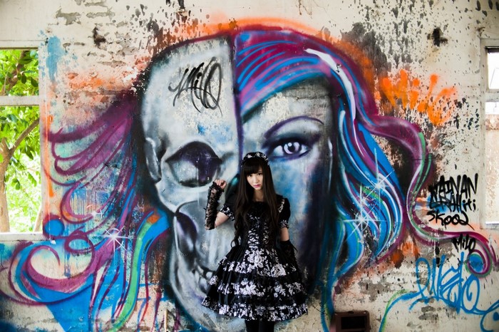Woman in Lolita dress in front of graffiti wall
