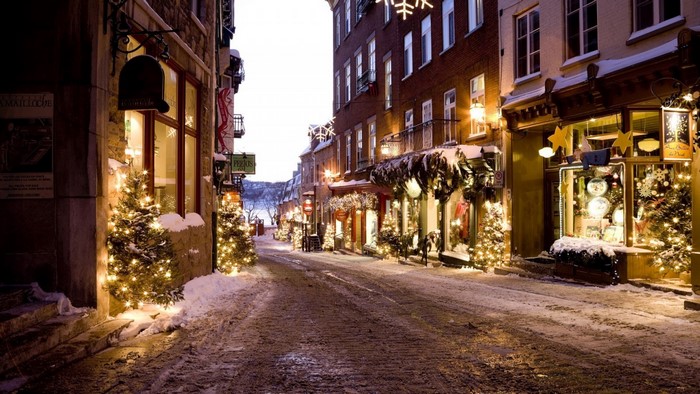 Snowy street decorated with Christmas lights at night