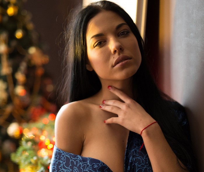 Woman with black hair and red nails near Christmas tree