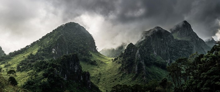 Misty mountain valley with green slopes and dark clouds