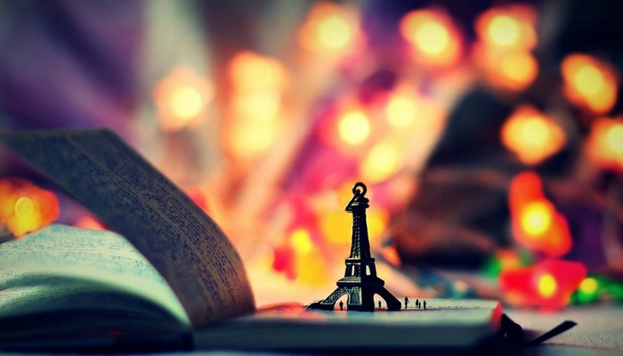 Eiffel Tower replica on an open book with bokeh lights