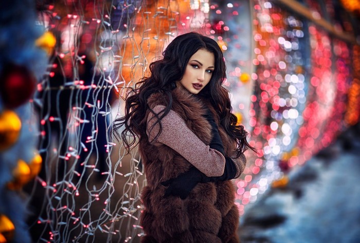 Woman in fur vest and gloves with bokeh lights