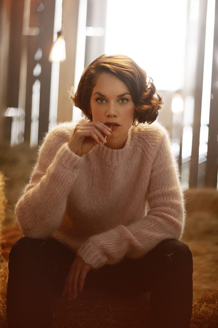 Ruth Wilson in a pink sweater sitting in a barn
