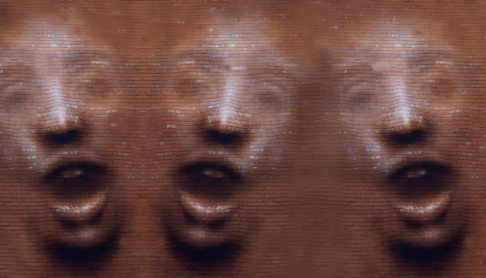 Faces emerging from a brick wall texture