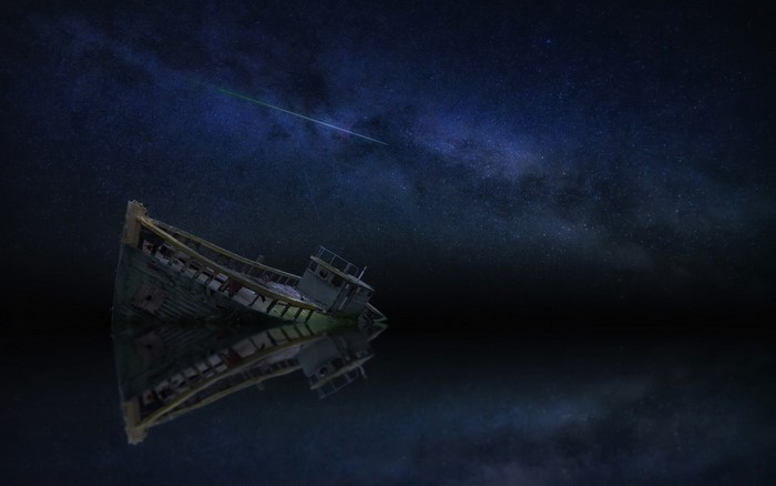 Wrecked boat under a starry night sky with a meteor