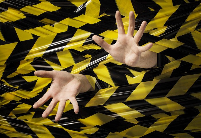 Hands trapped in yellow and black caution tape
