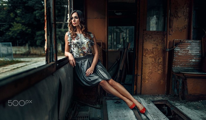 Woman in floral top and skirt sitting in a tram
