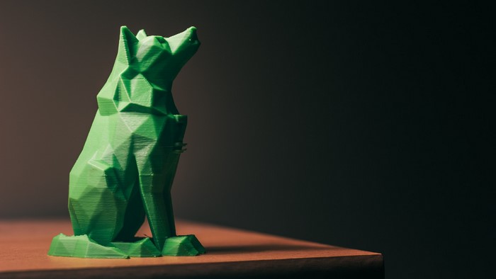 Green geometric wolf sculpture on a wooden surface