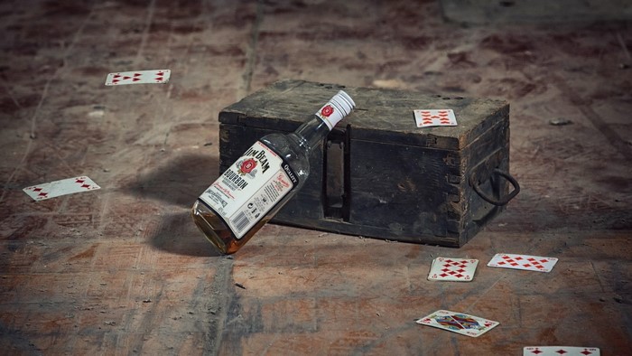 Jim Beam bottle and playing cards on wooden chest