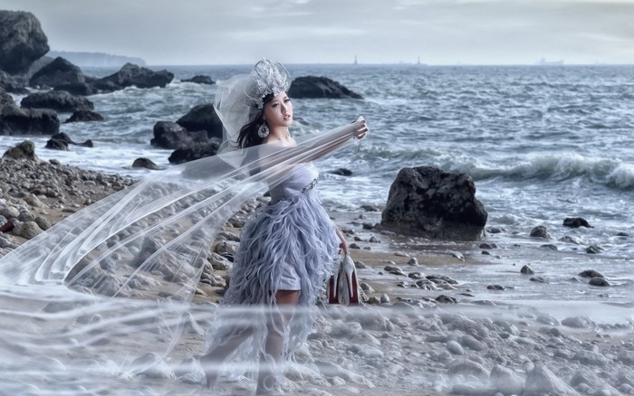 Woman in a dress on a rocky beach with the sea