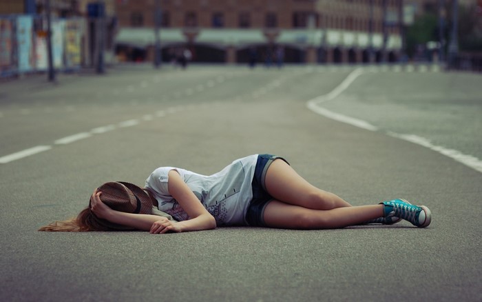 Woman in hat lying on road