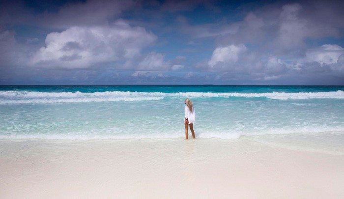 Woman in white shirt on a beach with waves