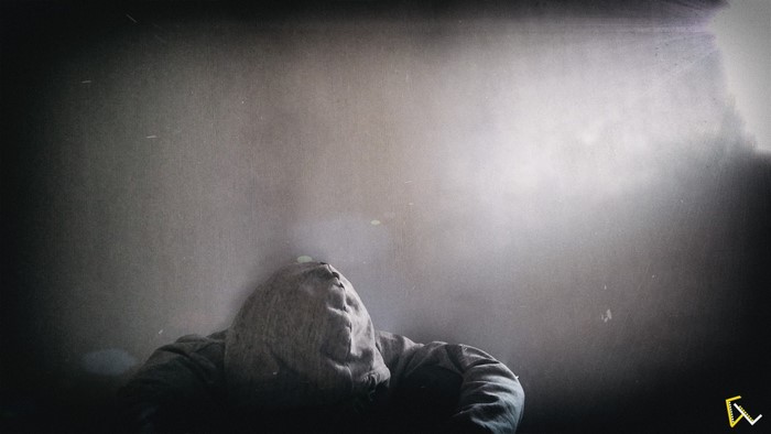 Person in a hoodie looking up in a dark room with light effects